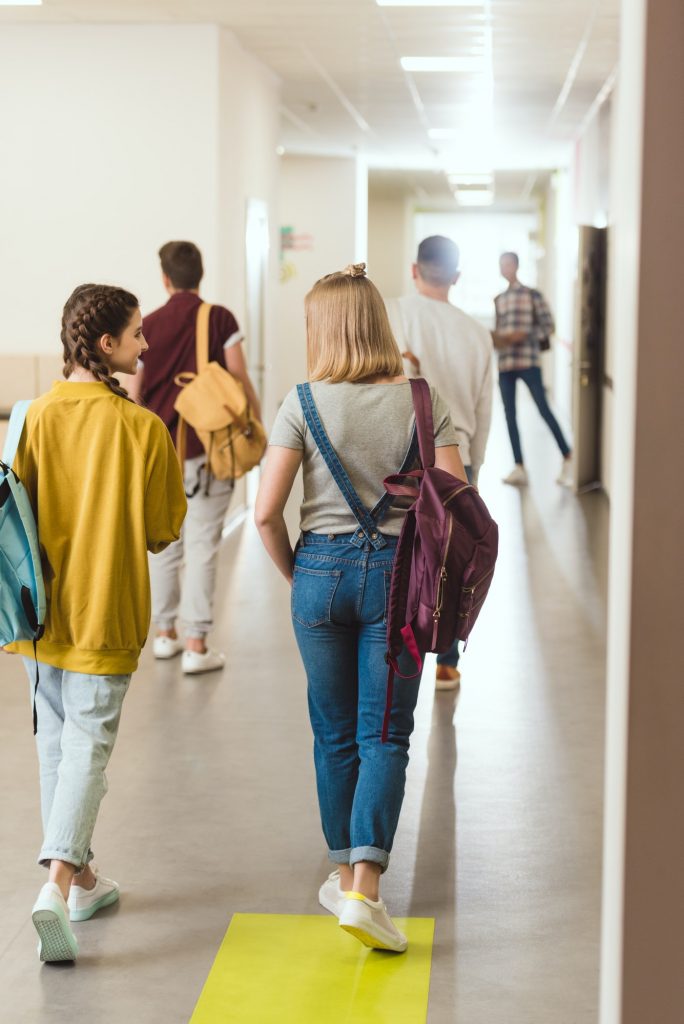 rear view of high school students walking by school corridor