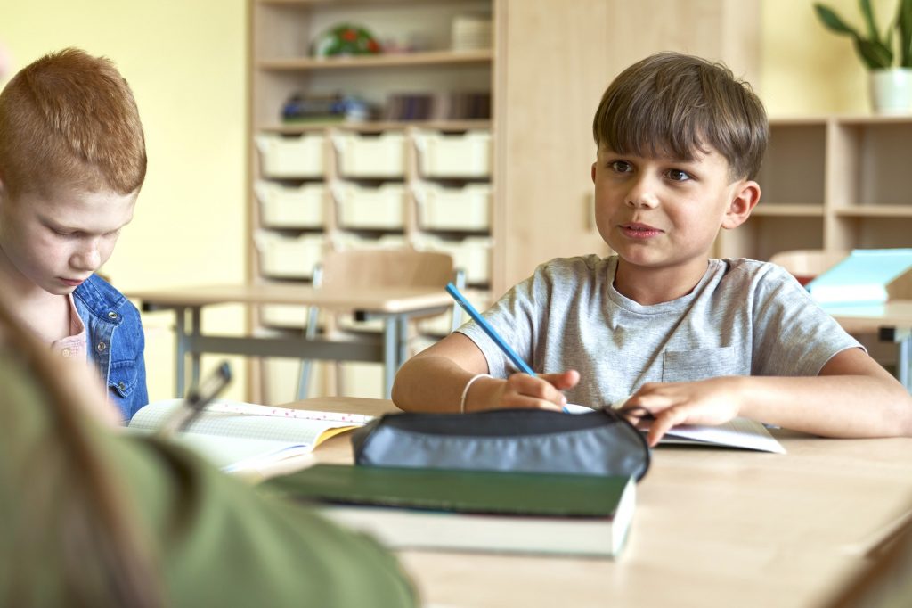 Schoolboy writing at school desk